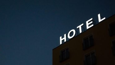 low-angle photo of Hotel lighted signage on top of brown building during nighttime